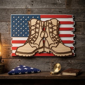 Pode incluir: Obra de arte em madeira com um par de botas de combate bege e placas de identificação, contra uma bandeira americana desgastada. As botas têm contornos castanhos e atacadores detalhados. A bandeira tem um campo de estrelas azul e listras vermelhas e brancas.