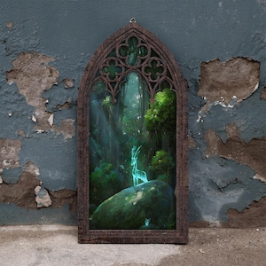 May include: A dark brown wooden wall hanging featuring a pointed gothic arch frame. The centre displays a vibrant forest scene with a glowing, translucent deer standing on a large mossy rock surrounded by lush green trees and foliage.