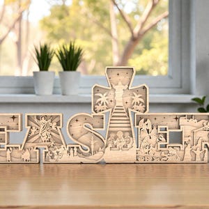 May include: A wooden Easter decoration spelling "EASTER" with detailed cut-out designs. The letters depict religious scenes, including a cross, Jesus, and other biblical figures. The decoration is crafted from light-coloured wood.