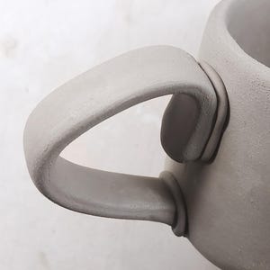 Close-up of round mug handle attached, handmade pottery template, beginner-friendly ceramic technique, perfect for DIY tea lover gifts.