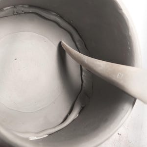 nside view of handmade round mug, strengthen the seams, slab-built using pottery template, smooth ceramic finish, showing DIY crafting process for beginner potters.