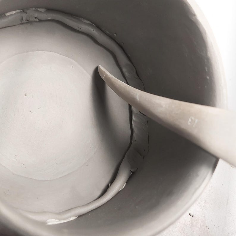 nside view of handmade round mug, strengthen the seams, slab-built using pottery template, smooth ceramic finish, showing DIY crafting process for beginner potters.