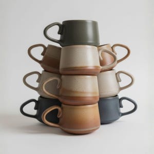Finished round ceramic mugs stacked on each other, created from handbuilt pottery template, ideal tea lover gift or kitchen decor.