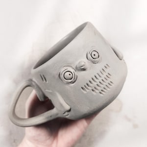 Handmade round mug with a penguin face sculpted on built with slab pottery technique, featuring unique texture and pottery template details, beginner-friendly ceramic tool.