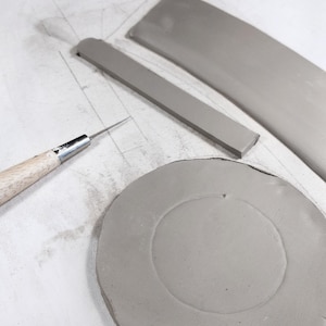 Pottery slab with cut mug parts and DIY pottery template, easy handbuilding for round ceramic mugs, essential tool for handmade pottery projects.
