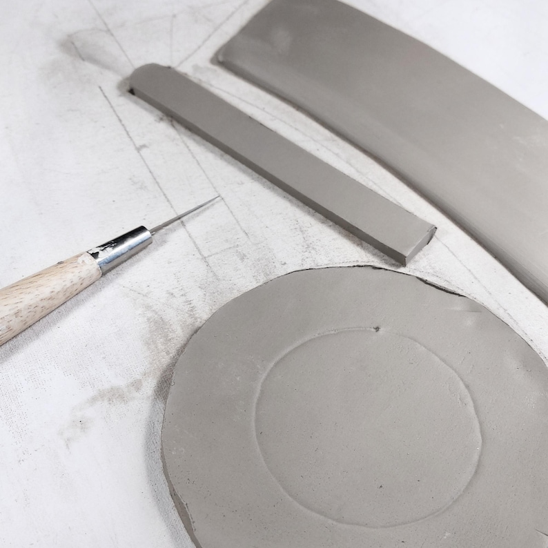 Pottery slab with cut mug parts and DIY pottery template, easy handbuilding for round ceramic mugs, essential tool for handmade pottery projects.
