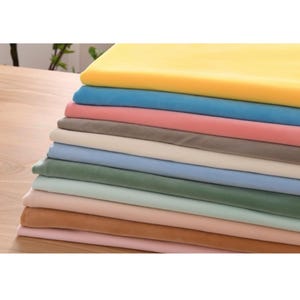 May include: A stack of fabric swatches in various colors, including yellow, blue, pink, gray, white, green, and brown. The fabric appears to be soft and velvety.