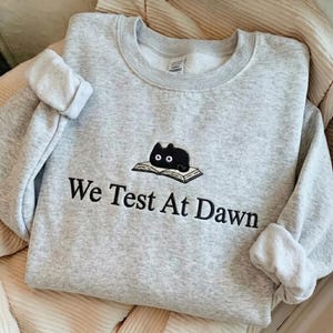 Embroidered Black Cat We Test At Dawn Sweatshirt, Funny Software Tester Crewneck, QA Engineer Gift,Coder Humor Shirt, Cat Lover Tech Apparel