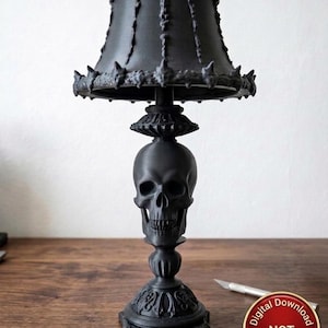 May include: A matte black table lamp featuring a skull-shaped base and a textured lampshade with vertical ribbing and small skull accents along the top and bottom edges. A circular badge in the corner reads Digital Download NOT physical item.