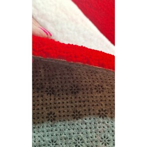 May include: Close-up of a layered textile with a red, white, and brown color scheme. The top layer is red, the middle layer is white, and the bottom layer is brown with a floral pattern.