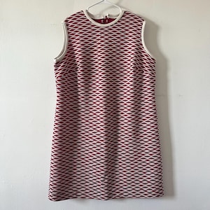 May include: A sleeveless shift dress featuring a repeating maroon and white diamond lattice pattern. The garment has a round neckline with white trim along the collar and armholes, and a straight silhouette that falls to the mid-thigh area.