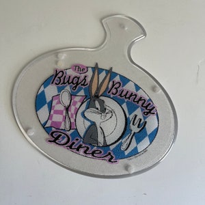 May include: A clear plastic plate with a blue and white checkered design. The plate features a cartoon image of Bugs Bunny with the text "The Bugs Bunny Diner".