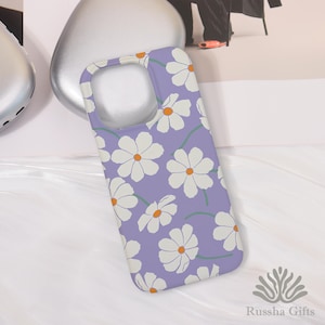 May include: A lavender phone case with a repeating pattern of white daisies with orange centers and green stems. The case has a smooth finish and a cutout for the camera and buttons. The brand name "Russha Gifts" is visible in the bottom right corner.