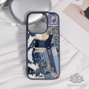 Może przedstawiać: Etui na telefon z ciemnoniebieską ramką i wzorem kolażu. Projekt zawiera ilustracje białych królików, czarnego kota, niebieskich książek i zabytkowych znaczków. Widoczny jest również tekst "dream a little dream of me".
