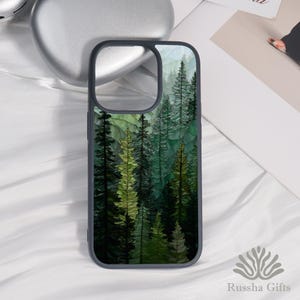 Può includere: Una custodia per telefono con un design a tema foresta. La custodia presenta un bordo grigio scuro e un'immagine vibrante di alberi verdi e gialli. L'opera d'arte raffigura una fitta foresta con alberi alti e sottili, creando un'estetica naturale. La custodia è progettata per proteggere il telefono.