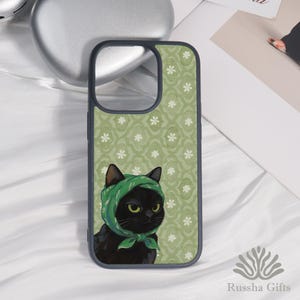 May include: A phone case featuring a black cat wearing a green headscarf. The case has a green floral pattern background. The case is dark gray with a cutout for the camera and buttons. The brand name "Russha Gifts" is at the bottom.