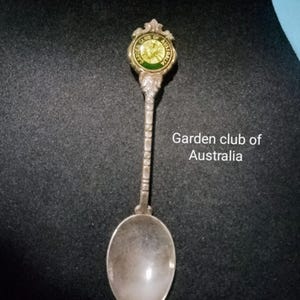 Könnte beinhalten: Silberne Souvenirlöffel mit einem grünen und goldenen Emaille-Design mit dem Text "Garden Club of Australia".