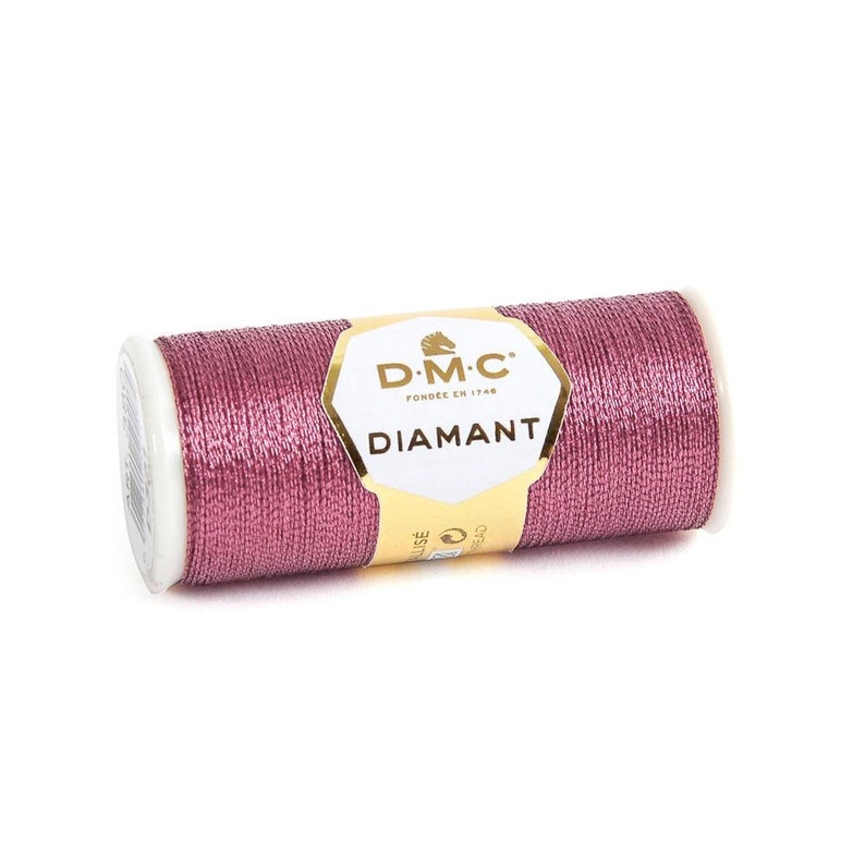 May include: A spool of DMC Diamant metallic embroidery thread in a pink shade. The spool has a gold label with the DMC logo and the text "Diamant" in gold lettering.