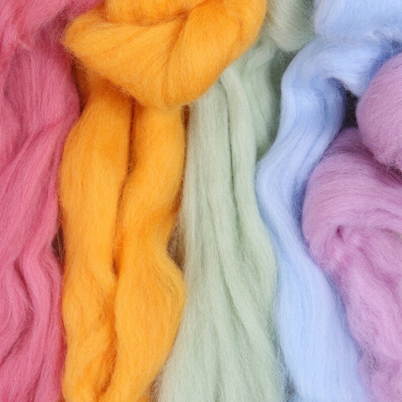 May include: Close-up of five strands of colorful wool yarn in pink, orange, green, blue, and purple. The yarn is soft and fluffy, and the colors are vibrant.