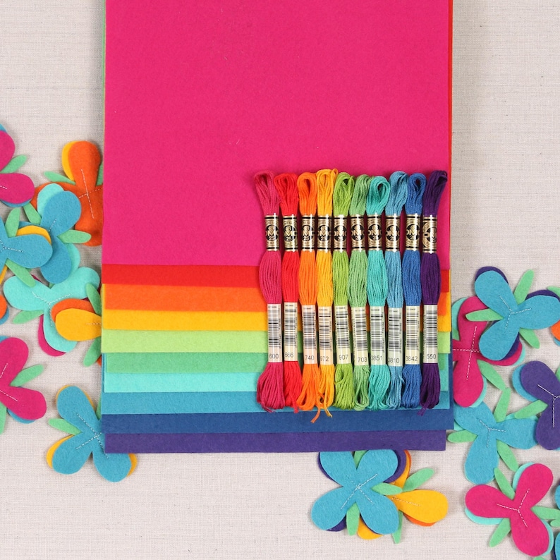 Pu&ograve; includere: Un assortimento di fogli di feltro arcobaleno e filo da ricamo per l'artigianato. I fogli di feltro sono disposti a forma di arcobaleno, con il foglio superiore rosa e il foglio inferiore viola. Ci sono 10 rocchetti di filo da ricamo in vari colori, tra cui rosso, arancione, giallo, verde, blu e viola.
