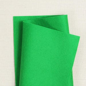 Könnte beinhalten: Ein Blatt hellgrüner Filzstoff, in der Mitte gefaltet. Der Filz ist glatt und hat eine weiche Textur.