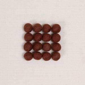 May include: A square arrangement of twenty brown felt balls.