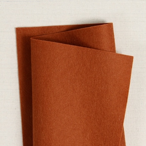 May include: A sheet of brown felt fabric folded in half. The felt is a rich, deep brown color and has a soft, fuzzy texture.