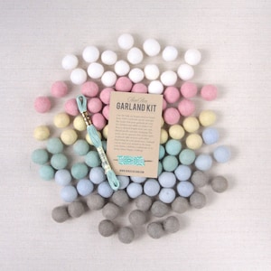 May include: A garland kit with a variety of felt balls in white, pink, yellow, blue, and gray colors. The kit includes a spool of thread and a card that reads "Gem & Home Garland Kit".