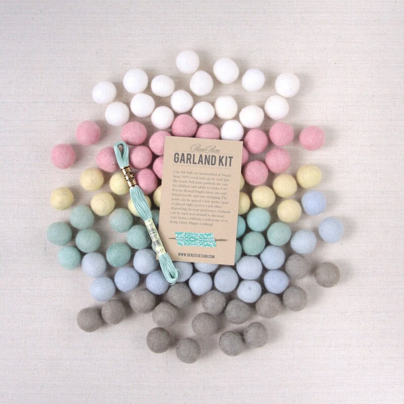 May include: A garland kit with a variety of felt balls in white, pink, yellow, blue, and gray colors. The kit includes a spool of thread and a card that reads "Gem & Home Garland Kit".