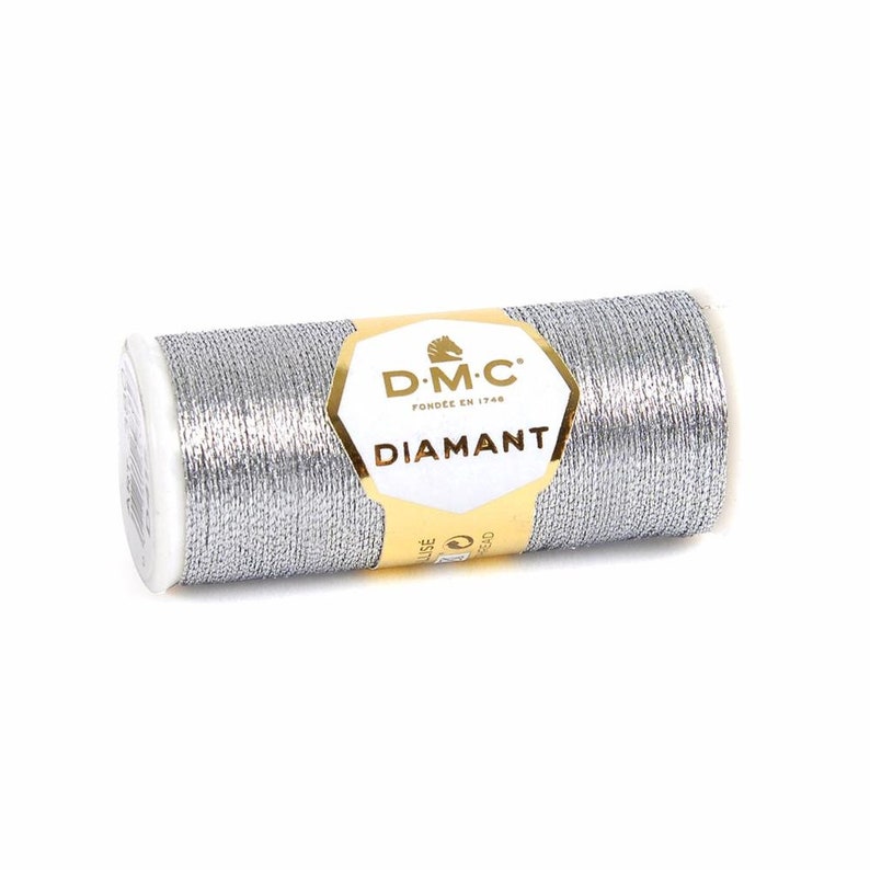 May include: A silver metallic thread spool with the DMC Diamant brand label. The label is gold with black text and features a horse logo.