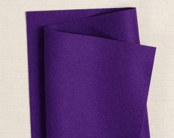 Puede incluir: Una hoja de fieltro morado doblada por la mitad. El fieltro es de un color morado intenso y rico.