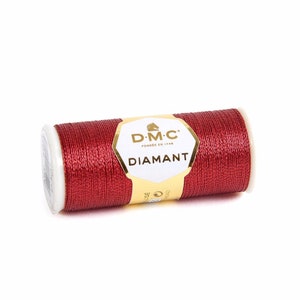 May include: A spool of DMC Diamant metallic thread in a deep red color. The spool is labeled with the DMC logo and the text "Diamant".