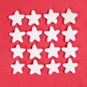 May include: A red felt background with 15 white felt stars arranged in a grid pattern.
