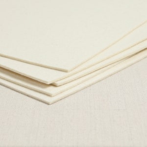 May include: A stack of five white felt squares, likely for crafting or other projects.