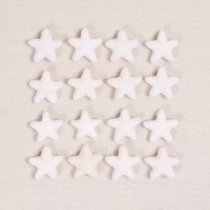 May include: A collection of 15 white felt stars, with one star in the center being a slightly off-white color.