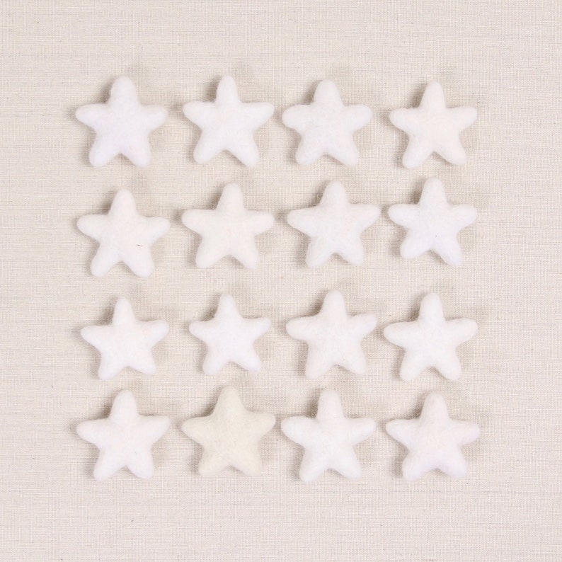 May include: A collection of 15 white felt stars, with one star in the center being a slightly off-white color.