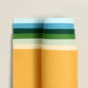 May include: A stack of felt fabric sheets in various colours, including light blue, dark blue, green, light green, cream, and yellow.