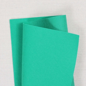 May include: A folded sheet of bright teal green felt fabric.