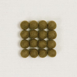 May include: Sixteen olive-green felt balls arranged in a grid pattern. The balls are evenly spaced and appear to be handmade. The background is a plain, off-white fabric, providing a neutral backdrop for the colorful spheres. These could be used for crafts or home decor.