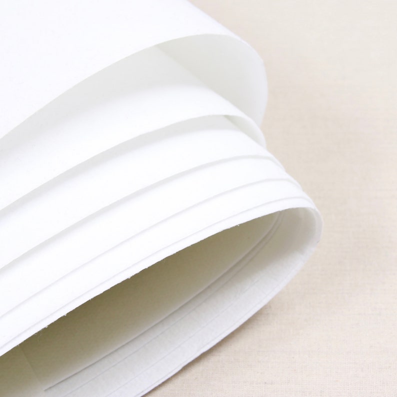 May include: Close-up of a stack of white paper, rolled up and showing the edges of the paper.