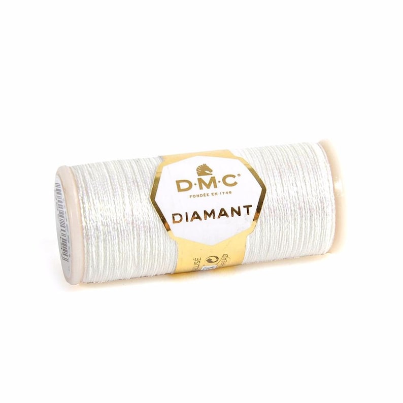 May include: A spool of white DMC Diamant thread with a gold label that says "DMC" and "Diamant".