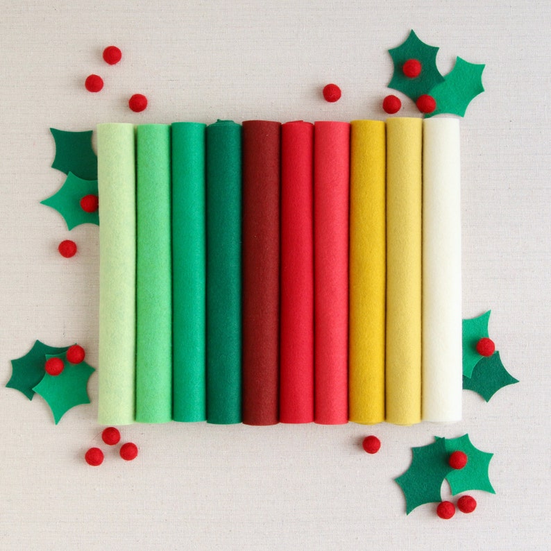 May include: Assortment of ten felt sheets in various colours, including green, red, yellow, and white. The felt sheets are rolled up and arranged in a row.