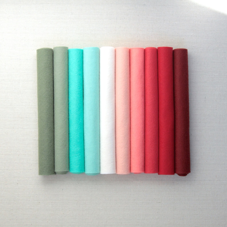 Puede incluir: Diez rollos de tela de fieltro en varios tonos de verde, azul, blanco, rosa y rojo. Los rollos est&aacute;n dispuestos en un degradado de verde a rojo.
