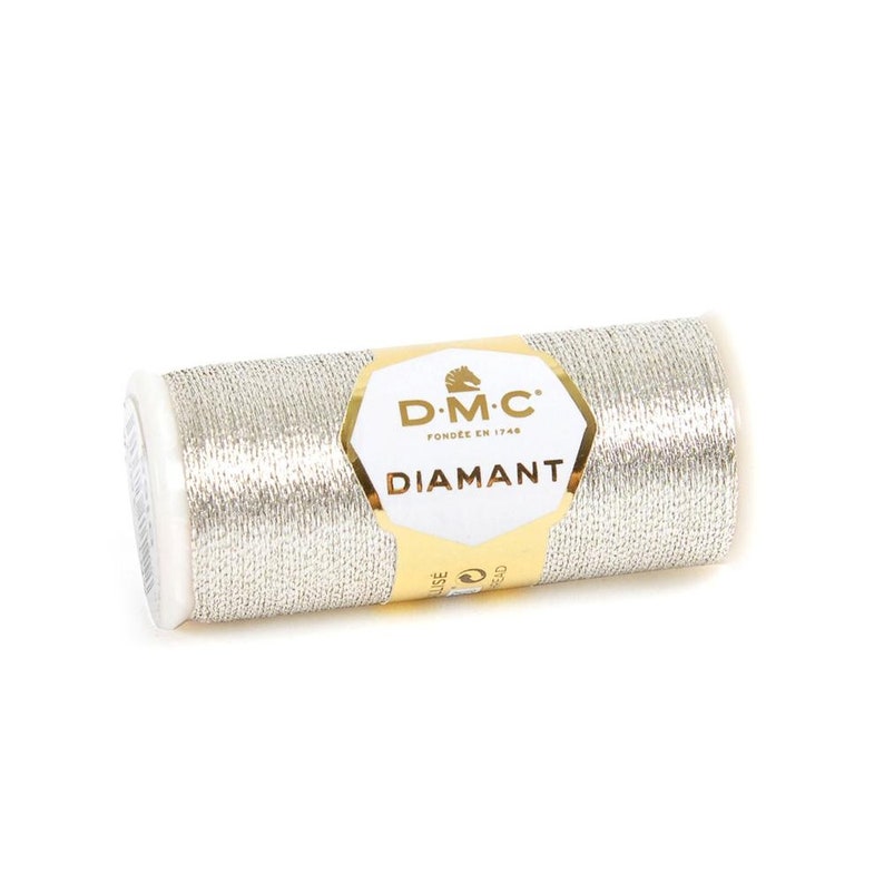 May include: A spool of silver metallic thread with a gold label that reads "D.M.C. Fond&eacute;e en 1748 Diamant".