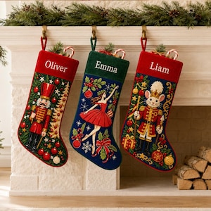 Könnte beinhalten: Drei personalisierte Weihnachtsstrümpfe mit Stickereimotiven. Der erste ist rot-grün mit einem Nussknacker, der zweite dunkelgrün mit einer Ballerina und der dritte dunkelblau mit einer Maussoldatenfigur. Die Namen Oliver, Emma und Liam sind auf die Bündchen gestickt.