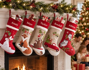 Op de afbeelding: Vijf kerstsokken hangen aan een schoorsteenmantel, elk met een witte boord en geborduurde naam: Annie, Maya, Tucker, Kendall en Allison. De sokken tonen feestelijke applicaties waaronder een konijn, vos, eekhoorn, rode vrachtwagen en uilen.