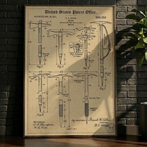 Pode incluir: Ilustração de patente emoldurada de um machado de gelo, datada de 18 de abril de 1911, do United States Patent Office. O diagrama mostra várias vistas e componentes da ferramenta, com rótulos e medidas detalhadas. A impressão é em papel envelhecido.