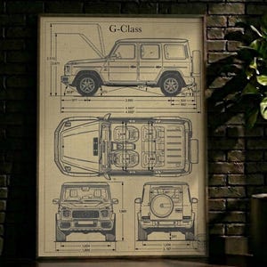 May include: A framed blueprint-style print of a G-Class SUV, showcasing top, side, front, and rear views with dimensions in inches. The print has a vintage aesthetic, with the text "G-Class" at the top.