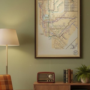 May include: A framed vintage NYC subway map hangs on a green wall. A retro radio sits on a wooden cabinet with books and a potted plant. A lamp and a patterned armchair are also in the room, creating a cozy, vintage aesthetic.