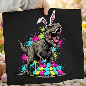 May include: Black canvas featuring a cartoon T-Rex wearing bunny ears, with an open mouth and colorful paint splatters. A pile of Easter eggs in yellow, blue, and pink is at the dinosaur's feet. The image has a fun, holiday theme.
